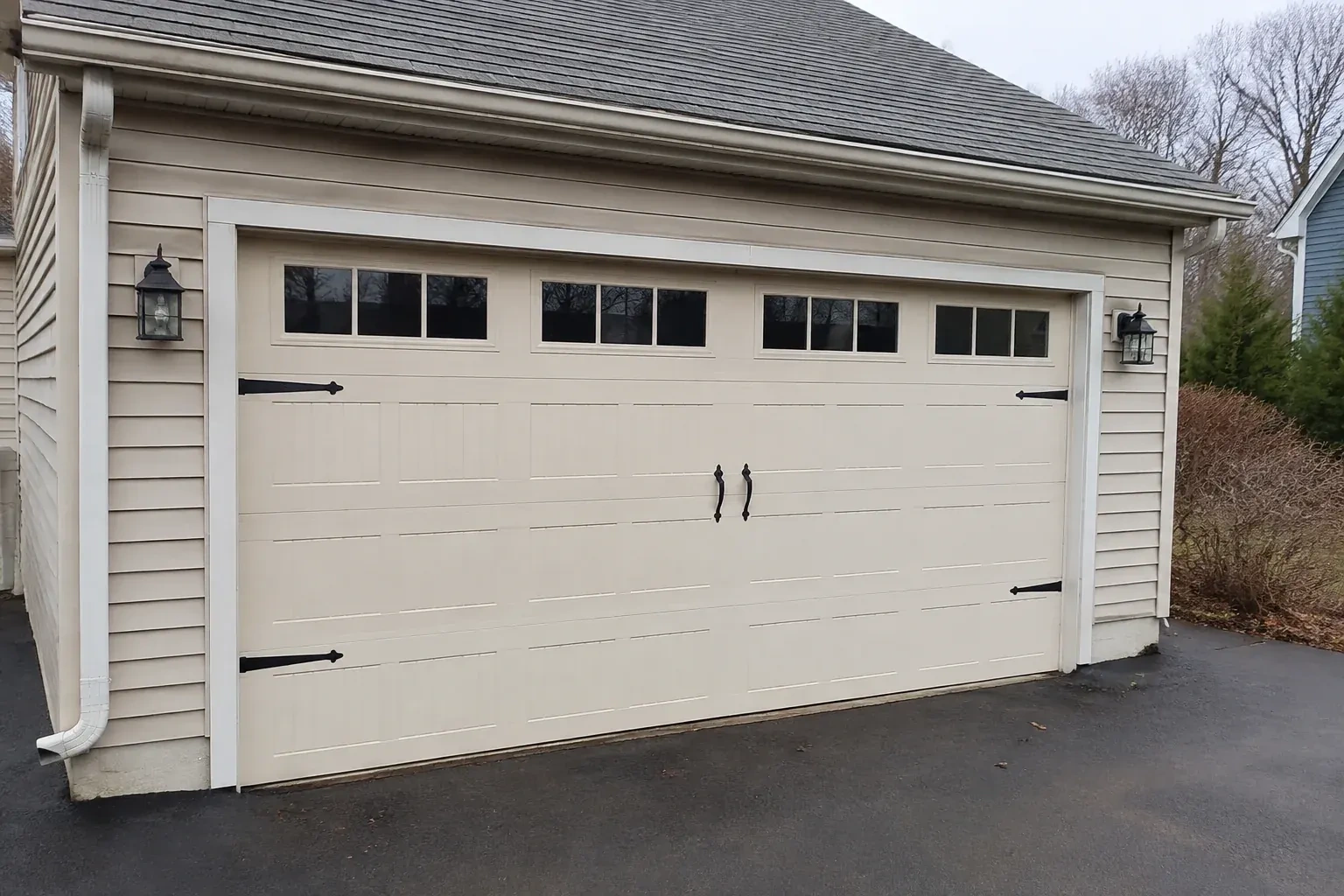 Cream carriage-house-style garage door with dark decorative hardware. — Carriage-House Garage Door Installation, Port Colborne