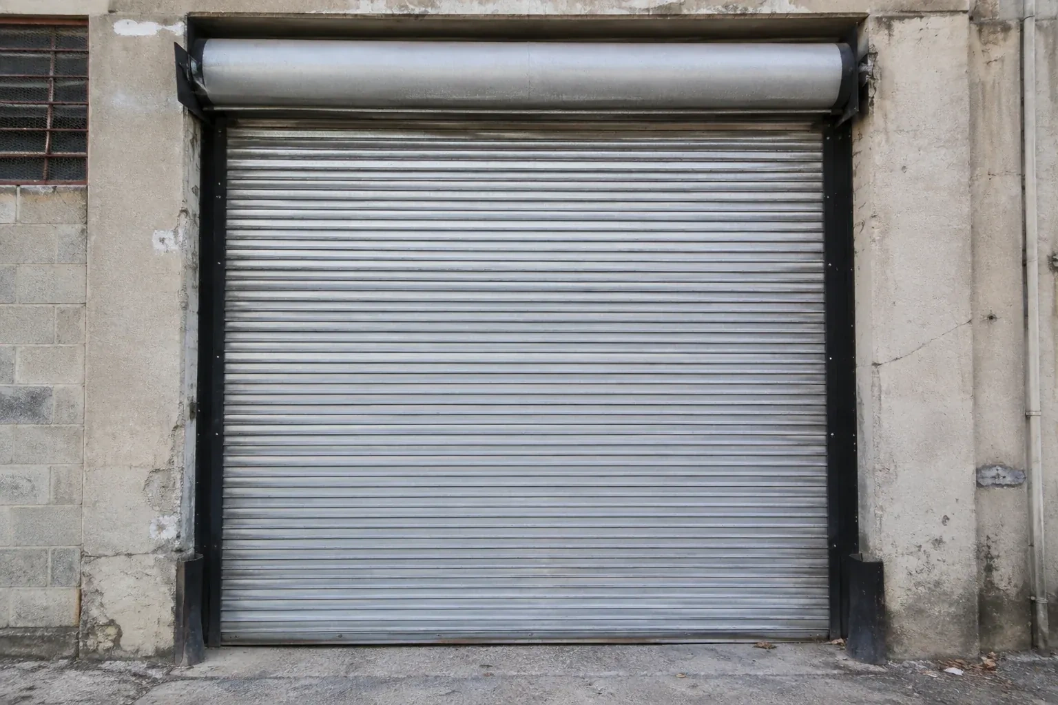 Closed metal rolling shutter in a weathered warehouse opening. — Commercial Rolling Door Repair, Port Colborne