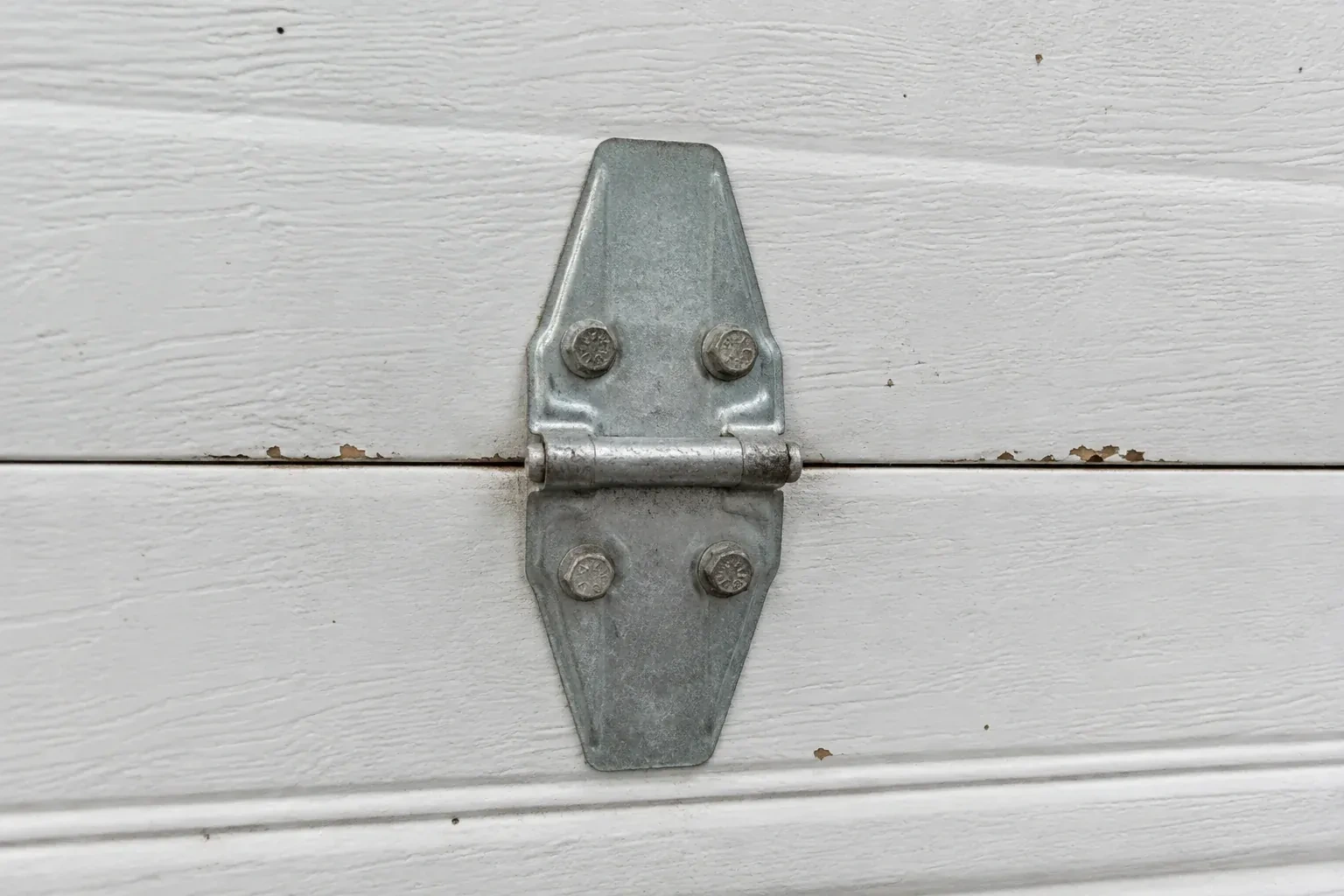 Metal center hinge across a seam in a white sectional garage door. — Garage Door Hinge Replacement, Port Colborne
